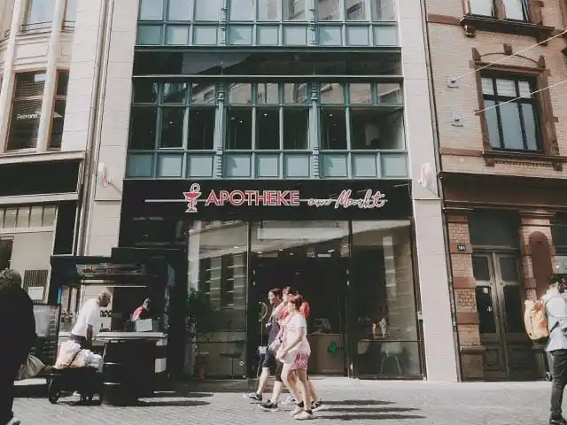 Außenansicht der Apotheke am Markt in Halle mit vorbeilaufenden Passanten
