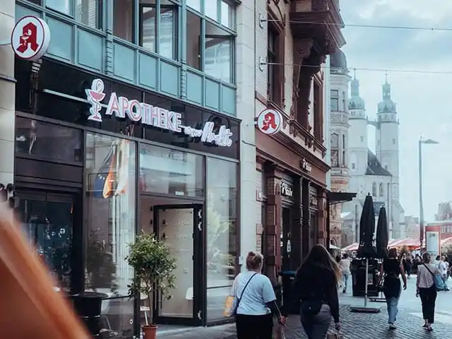 Apotheke am Markt in Halle mit Passanten und Blick auf die Marktkirche