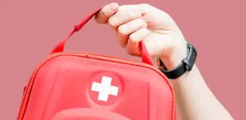 Hand hält roten Erste-Hilfe-Koffer mit weißem Kreuz